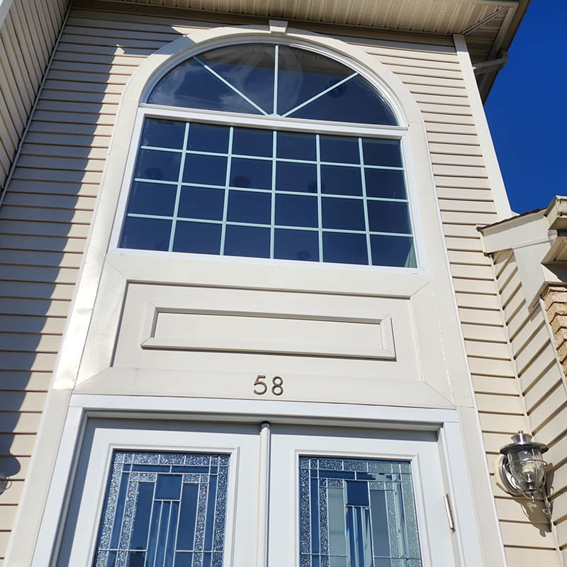 Photo of a grand arched window above an entryway. Window was installed by Everest Construction Group.